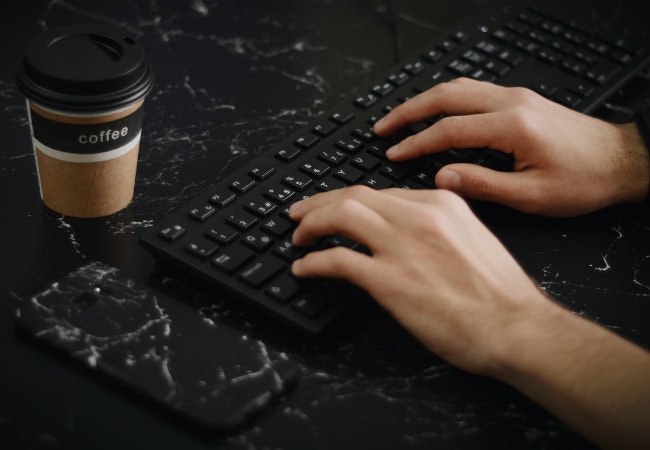 Mann sitzt am Desktop-PC und tippt an externer Tastatur. Bild: Pexels/Ekrulila